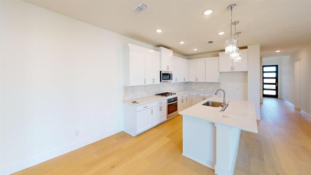 7013 Lathrop Lane Frisco, TX 75033 - Photo 5 of 26 Kitchen with an island with sink, white cabinetry, decorative light fixtures, and light wood-style floors