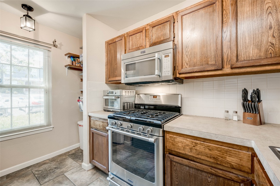 11821 Bittern Hollow, Unit 34 Austin, TX 78758 - Photo 7 of 24 Kitchen featuring stainless steel gas range oven, backsplash, light countertops, and brown cabinets