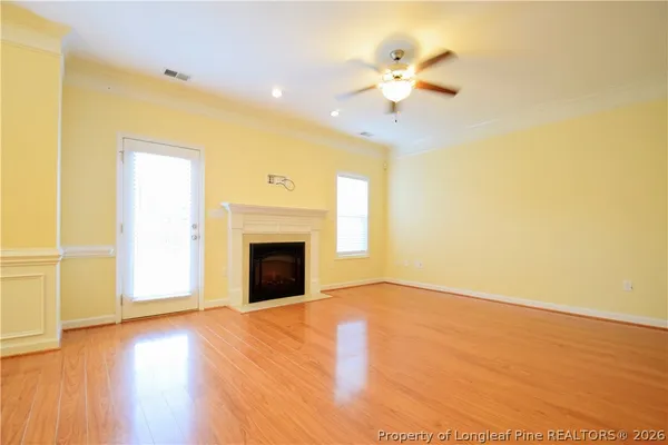 a view of an empty room with a fireplace and wooden floor