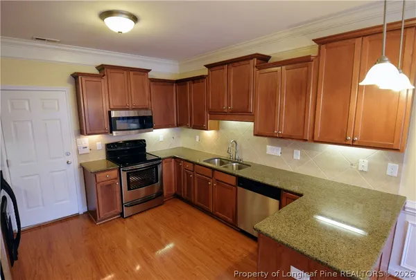 a kitchen with granite countertop wooden cabinets a stove top oven a sink and dishwasher