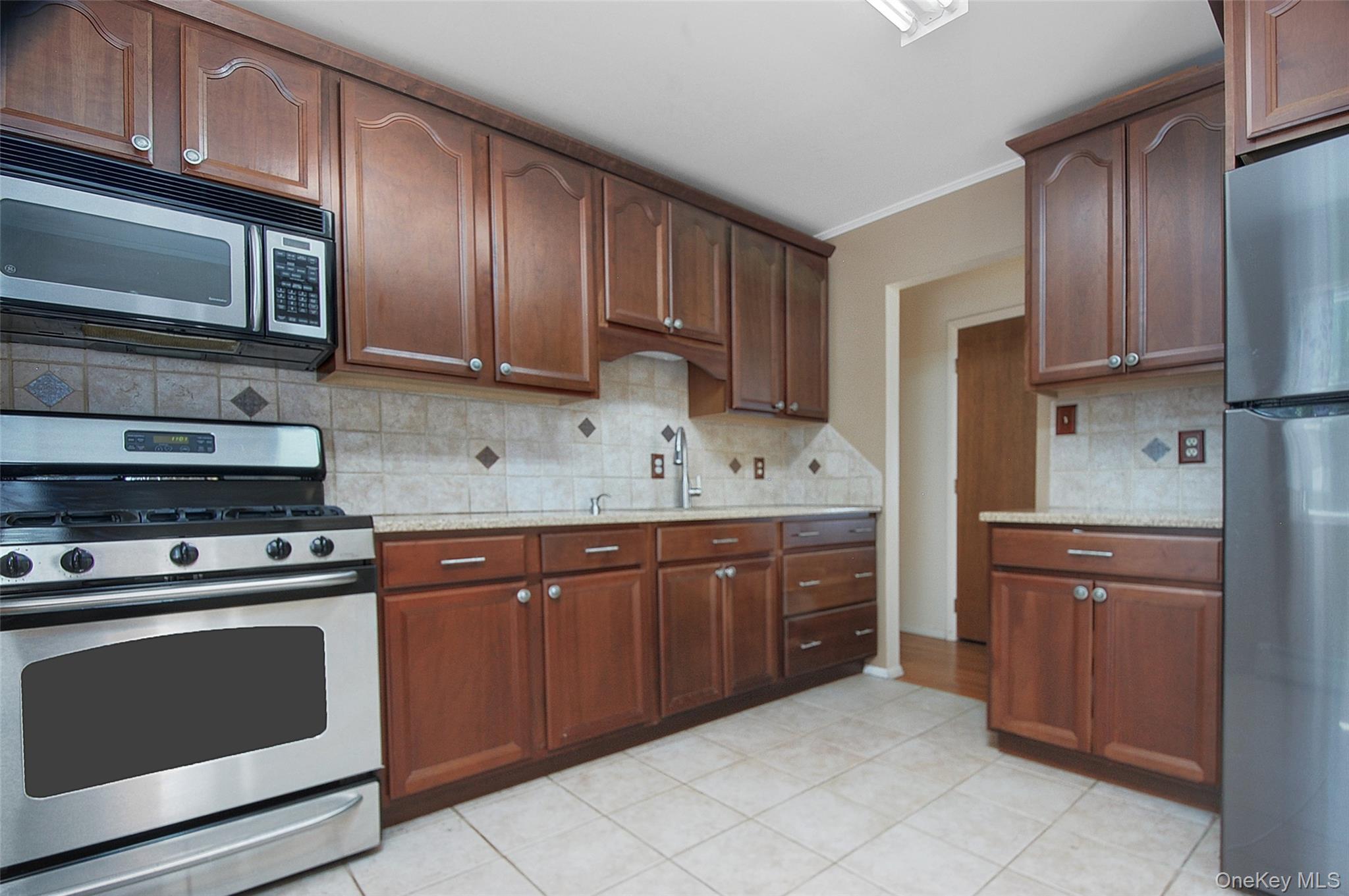 554 High Street Monroe, NY 10950 - Photo 16 of 29 a kitchen with stainless steel appliances granite countertop wooden cabinets a stove a sink and a microwave
