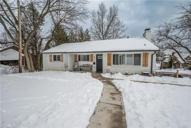 a front view of a house with a yard covered with snow and trees