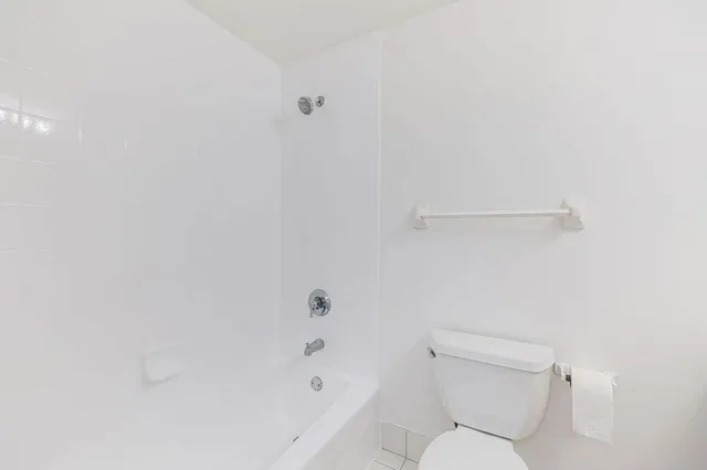 a white toilet sitting next to a bath tub