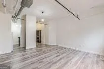 a view of a big room with wooden floor and windows