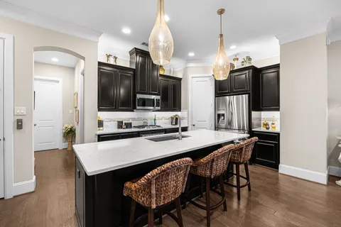 a kitchen with stainless steel appliances granite countertop a sink a stove a kitchen island with chairs and wooden floor