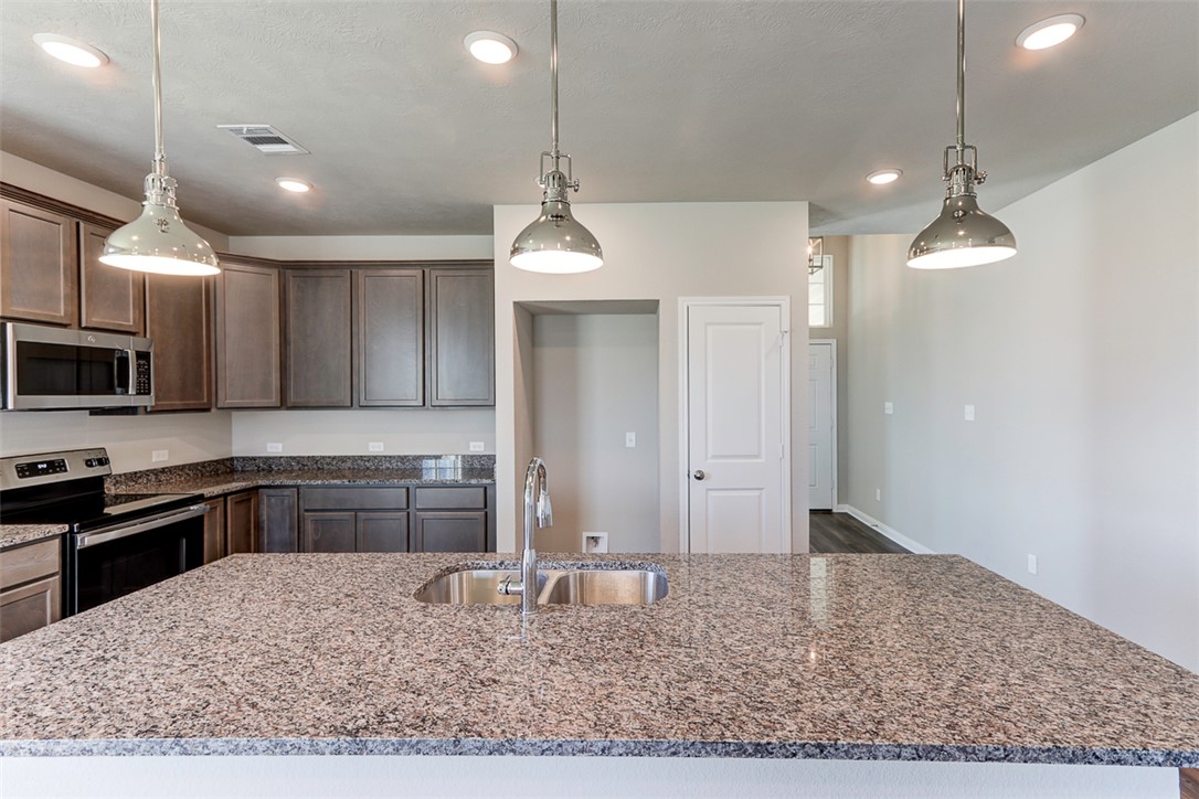 1937 Viva Road Bryan, TX 77807 - Photo 6 of 25 a kitchen with kitchen island granite countertop a sink cabinets and stainless steel appliances