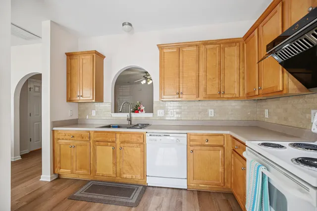 a kitchen with stainless steel appliances granite countertop a sink and cabinets with wooden floor