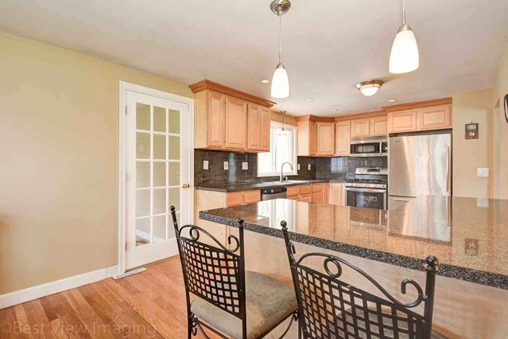 59 Amor Road Milton, MA 02186 - Photo 10 of 29 a kitchen with stainless steel appliances granite countertop a refrigerator a stove a sink a dining table and chairs with wooden floor