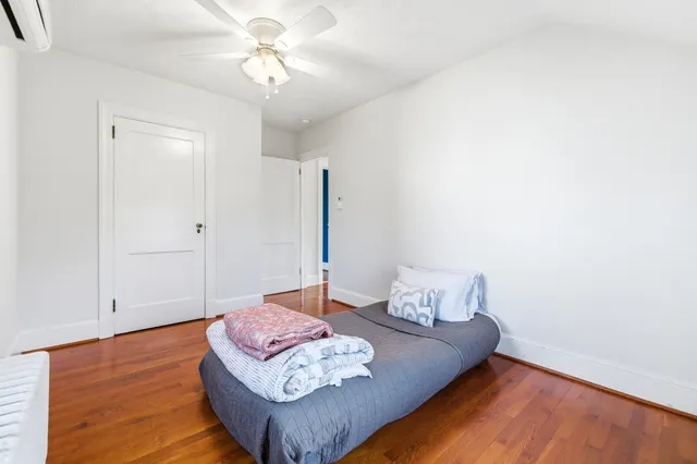 a view of an empty room with a window and wooden floor
