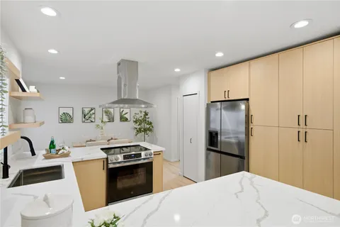 a kitchen with granite countertop a refrigerator stove and white cabinets