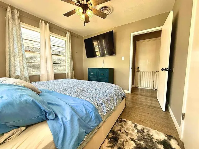a bedroom with a bed wooden floor and flat screen tv