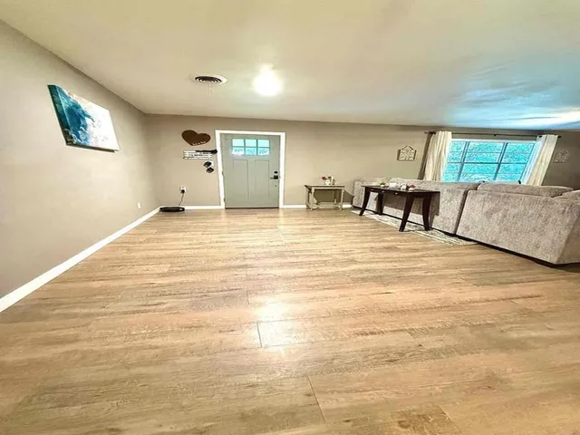 a view of an empty room with window and a kitchen