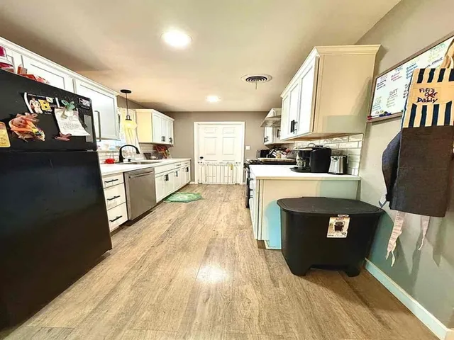 a large kitchen with stainless steel appliances granite countertop a stove a sink dishwasher and a refrigerator with wooden floor