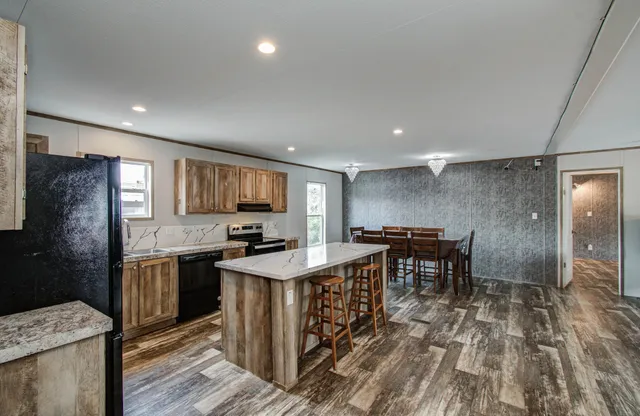a kitchen with kitchen island granite countertop a sink stove and refrigerator