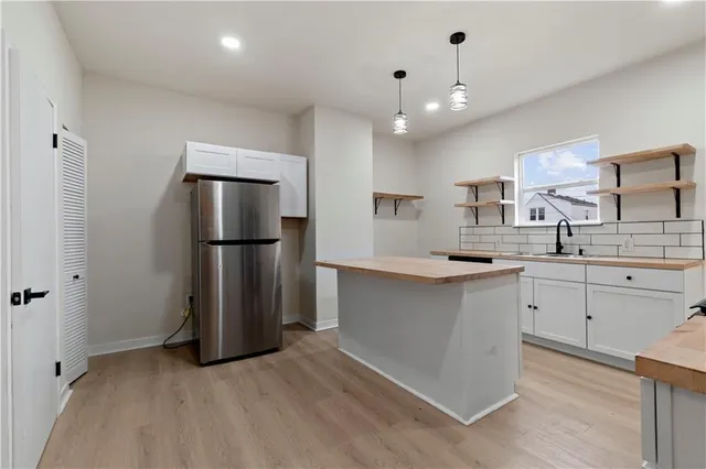 a kitchen with a refrigerator and white cabinets