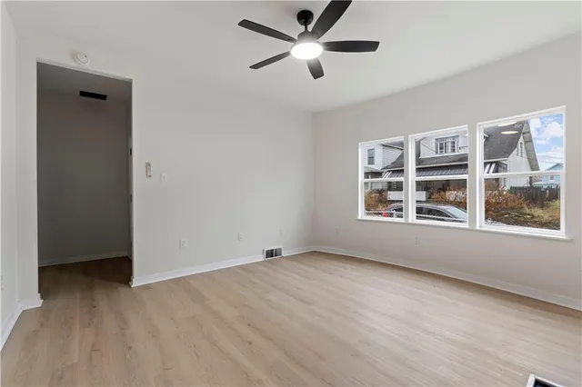 a view of an empty room with a window and wooden floor