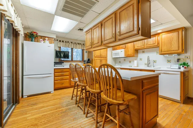 a kitchen with stainless steel appliances granite countertop a refrigerator a sink a stove and island with wooden floor