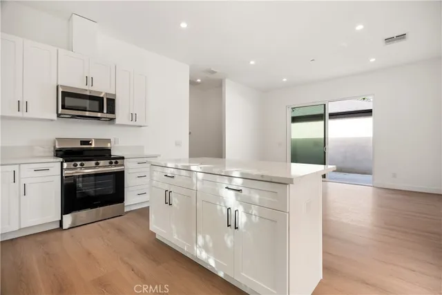 a kitchen with stainless steel appliances kitchen island granite countertop a stove a sink and a refrigerator