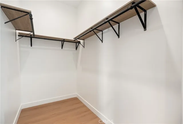 a view of an empty room with wooden floor and closet