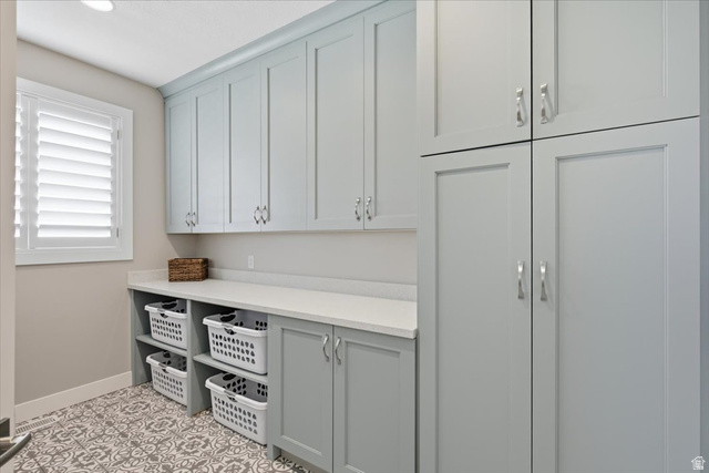 21 Pier Place Tooele, UT 84074 - Photo 40 of 112 Utility room featuring extensive built-in cabinetry, white countertops, decorative floor tiling, an integrated window, and recessed lighting