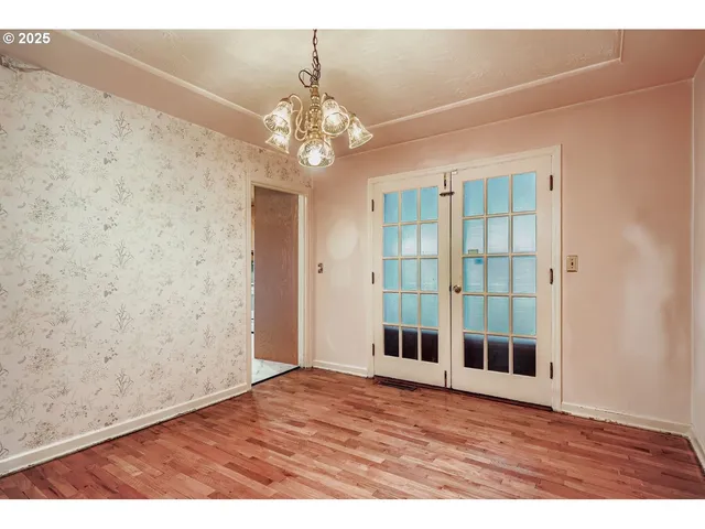 wooden floor in an empty room with a chandelier