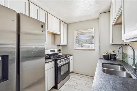 a kitchen with granite countertop a sink stove and refrigerator