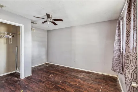 an empty room with wooden floor closet and windows