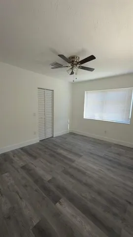 an empty room with wooden floor cabinet and windows