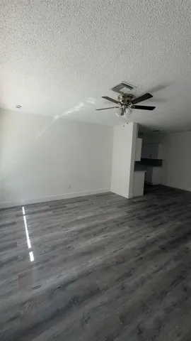 an empty room with wooden floor fan and windows