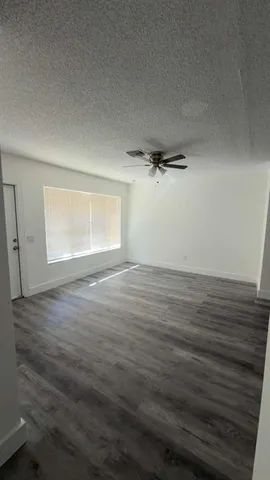 an empty room with wooden floor cabinet and windows