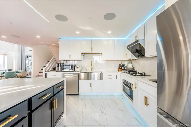a kitchen with a sink white cabinets and stainless steel appliances
