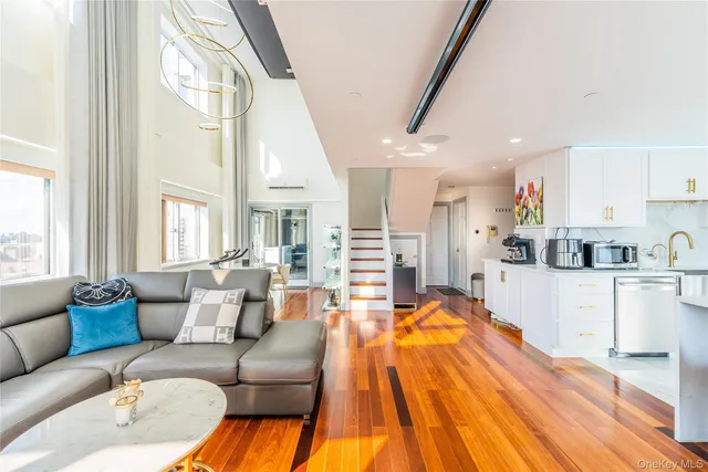 a living room with stainless steel appliances kitchen island granite countertop furniture and a wooden floor