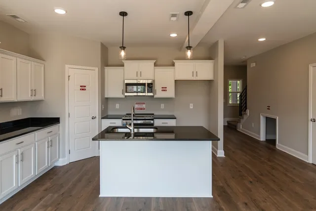 a kitchen with kitchen island a sink stainless steel appliances and wooden floor