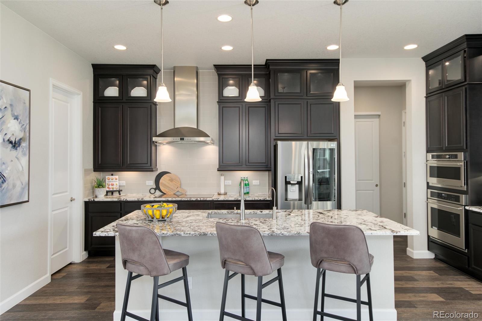 1165 Brocade Drive Highlands Ranch, CO 80126 - Photo 12 of 40 a kitchen with stainless steel appliances kitchen island granite countertop a refrigerator and wooden cabinets