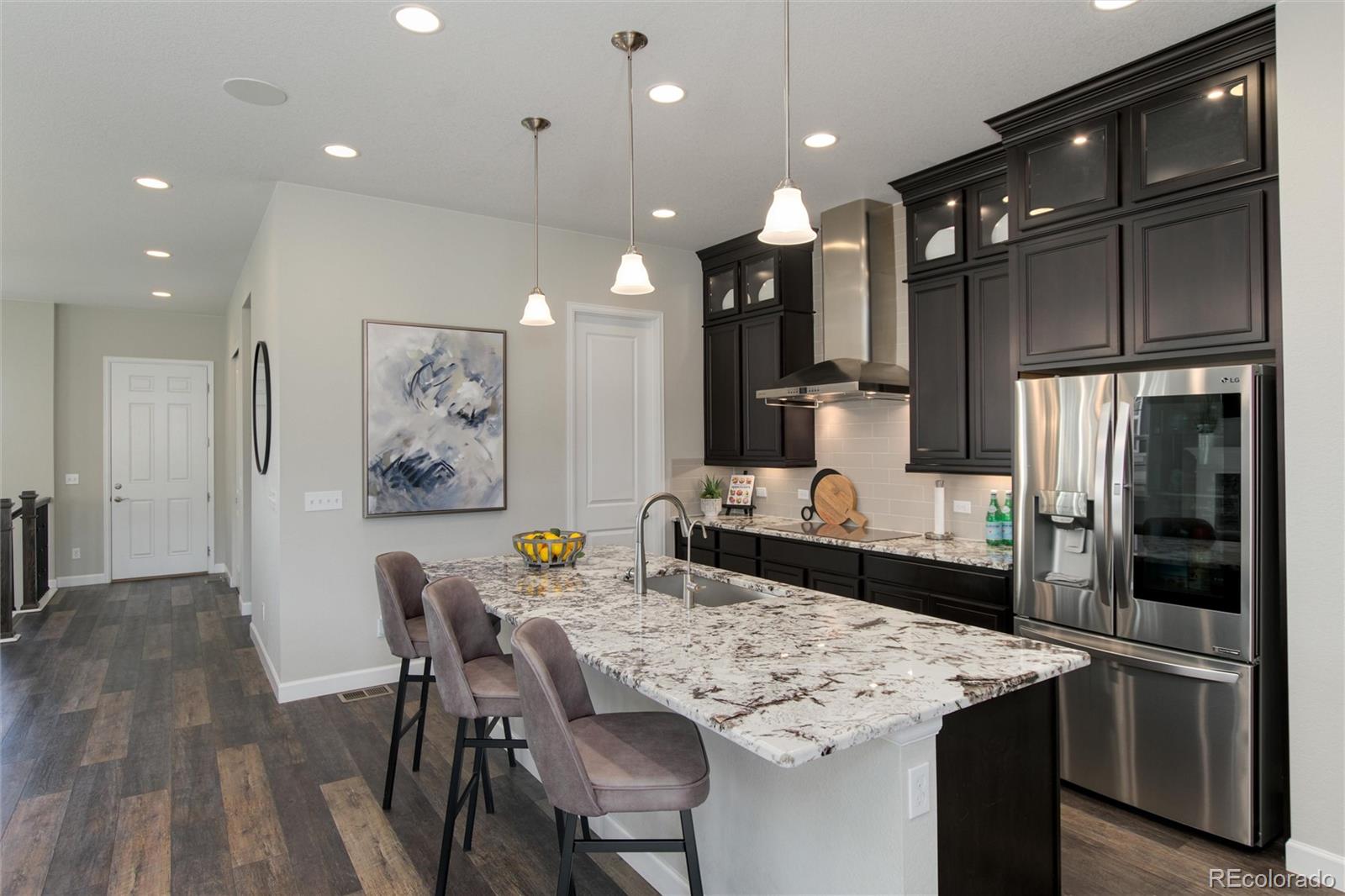 1165 Brocade Drive Highlands Ranch, CO 80126 - Photo 15 of 40 a kitchen with stainless steel appliances kitchen island granite countertop a kitchen island and chairs in it