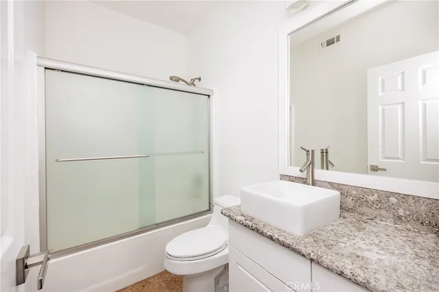 a bathroom with a granite countertop sink toilet and shower