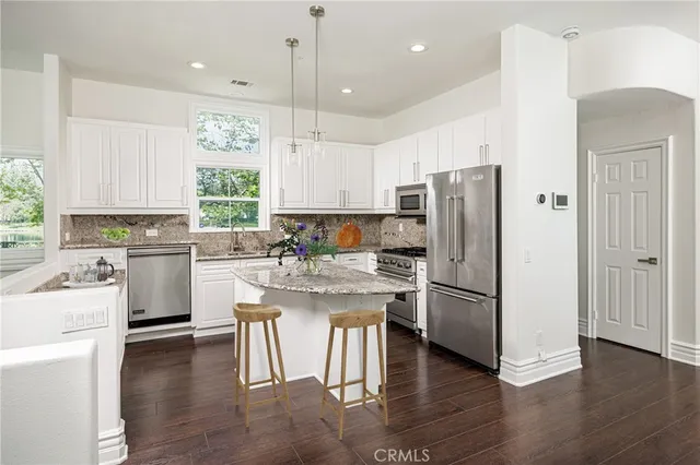a kitchen with a refrigerator a sink dishwasher a stove and white cabinets with wooden floor