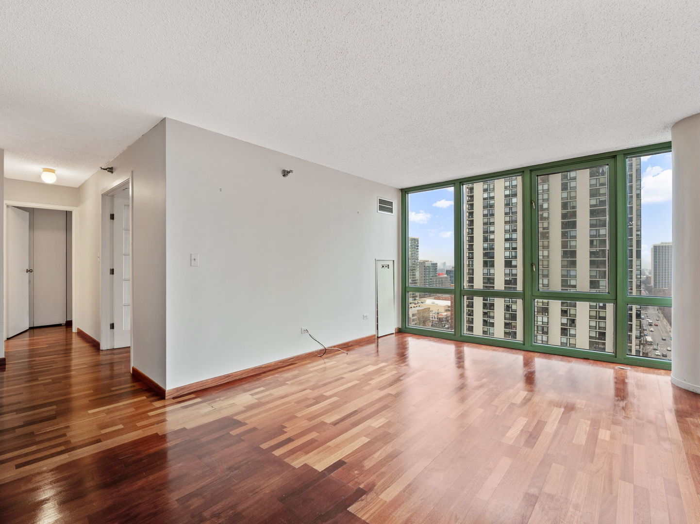 111 West Maple Street, Unit 1401 Chicago, IL 60610 - Photo 5 of 22 a view of an empty room with wooden floor and a window