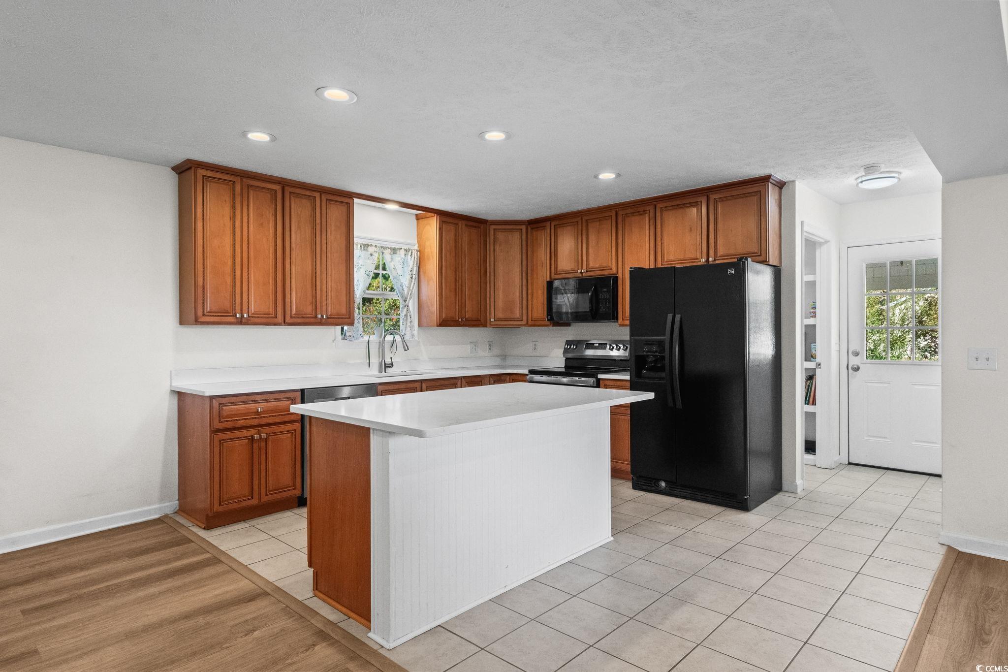 1996 Heritage Road Loris, SC 29569 - Photo 11 of 40 Kitchen with brown cabinets, black appliances, a center island, recessed lighting, and light wood-style floors