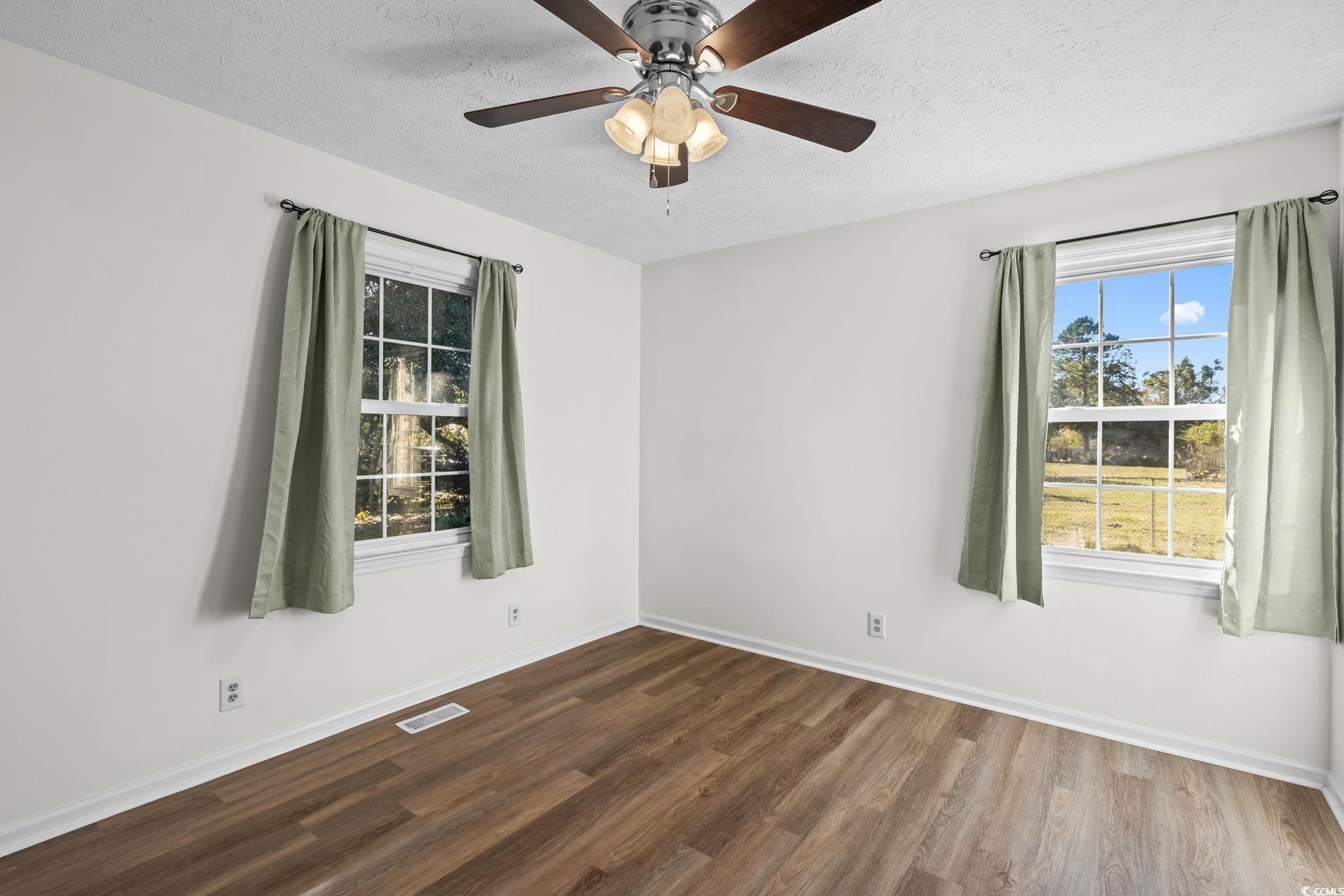 1996 Heritage Road Loris, SC 29569 - Photo 23 of 40 Empty room with wood finished floors, a textured ceiling, and ceiling fan