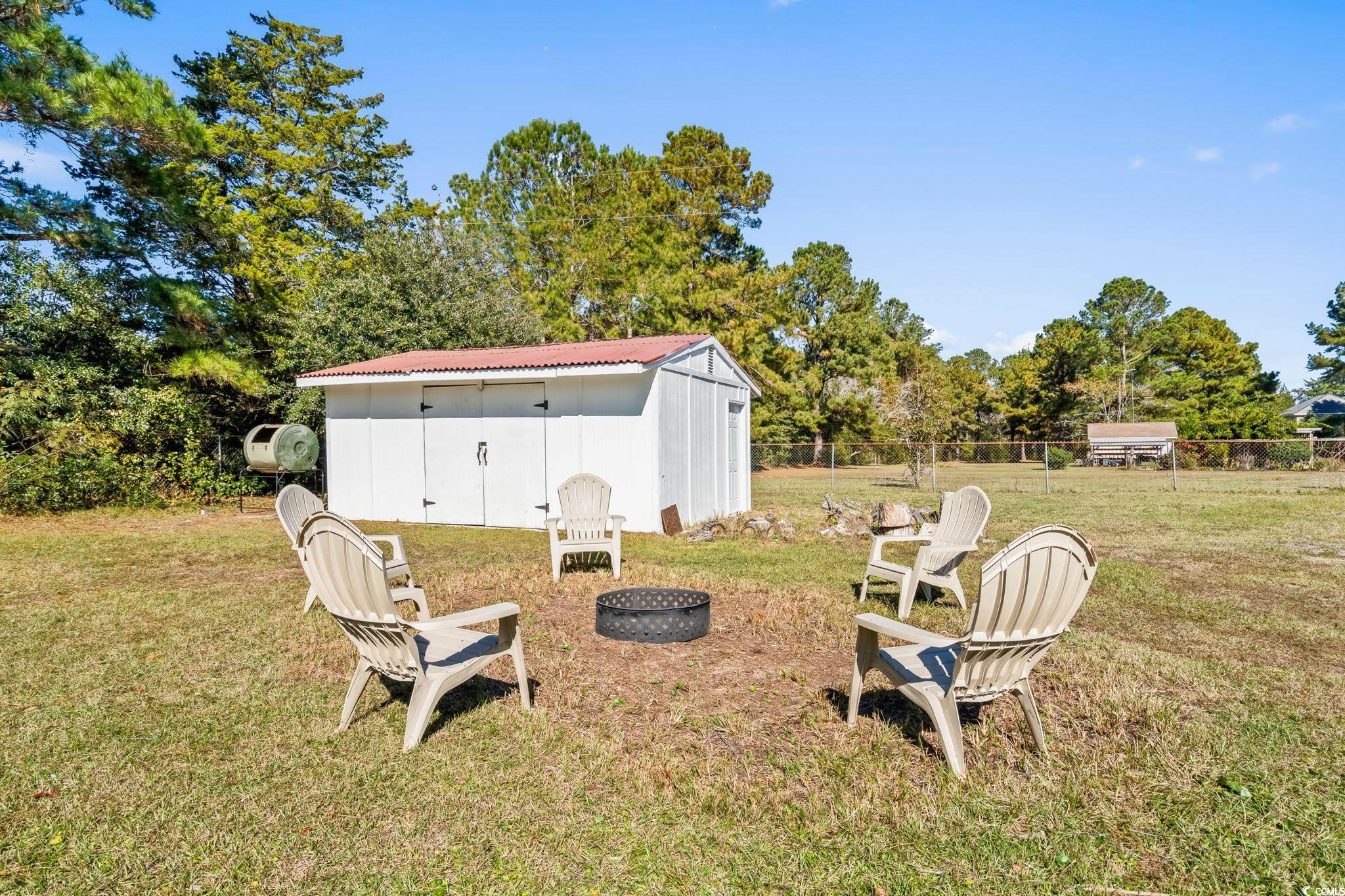 1996 Heritage Road Loris, SC 29569 - Photo 33 of 40 View of yard with an outdoor fire pit, view of wooded area, and a shed