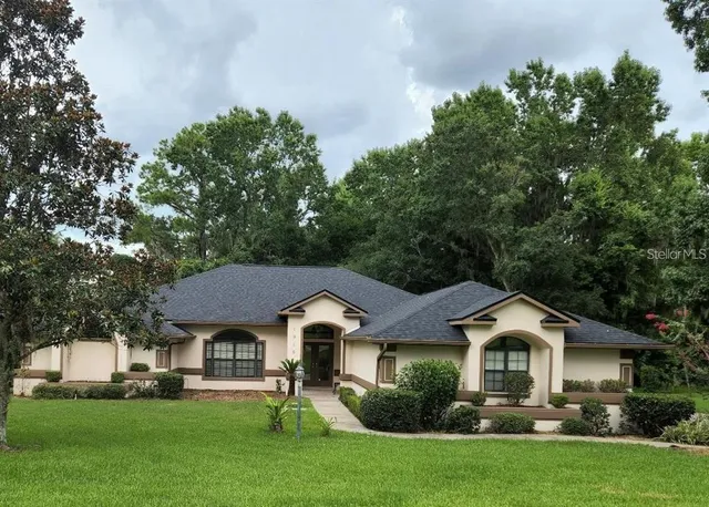 a front view of a house with a garden and trees