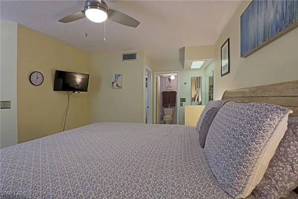 a bedroom with a bed and a flat tv screen on dresser