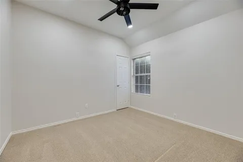 an empty room with a ceiling fan and window