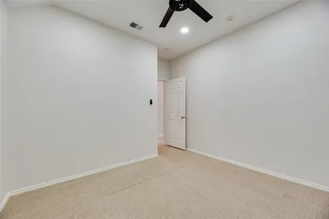an empty room with a ceiling fan and carpet