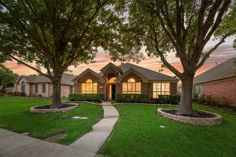 a front view of a house with a garden and trees