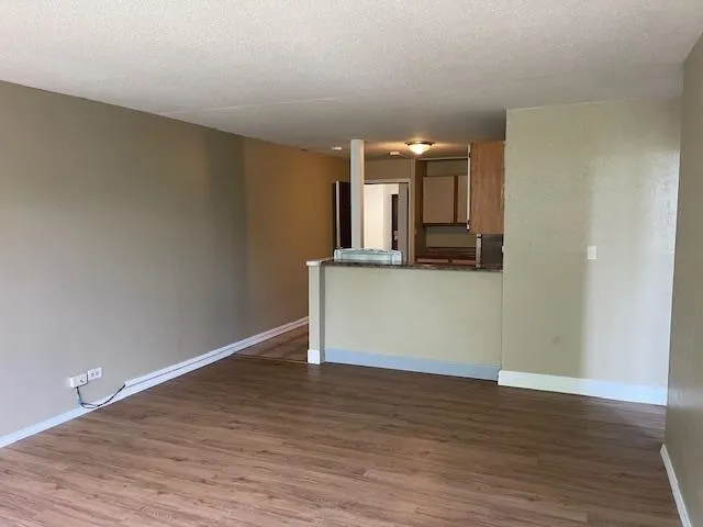 a view of a kitchen with wooden floor and white cabinets