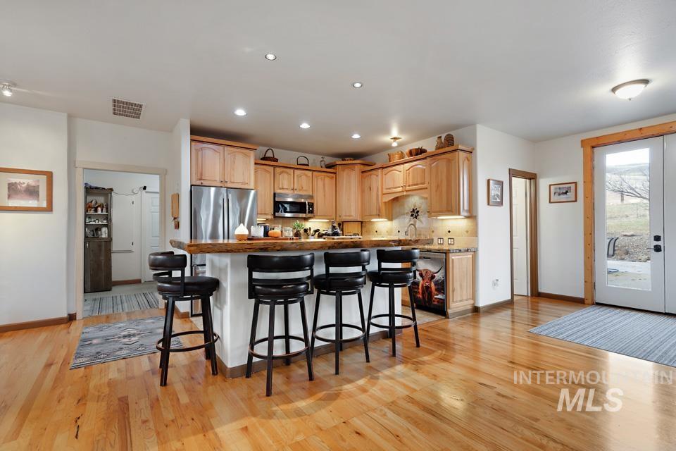 7025 Bluebird Lane Sweet, ID 83670 - Photo 15 of 46 Kitchen with a breakfast bar, appliances with stainless steel finishes, a kitchen island, light brown cabinetry, and french doors