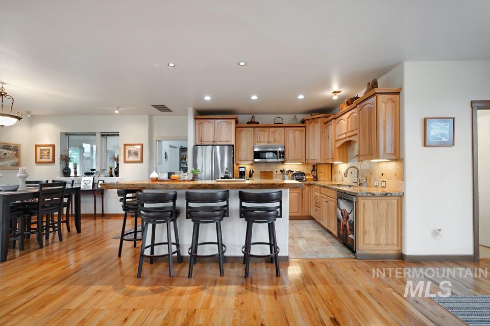 7025 Bluebird Lane Sweet, ID 83670 - Photo 16 of 46 Kitchen featuring a kitchen bar, stainless steel appliances, light wood-style flooring, recessed lighting, and a kitchen island