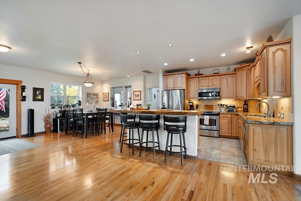 7025 Bluebird Lane Sweet, ID 83670 - Photo 17 of 46 Kitchen featuring stainless steel appliances, a kitchen breakfast bar, a kitchen island, decorative light fixtures, and decorative backsplash